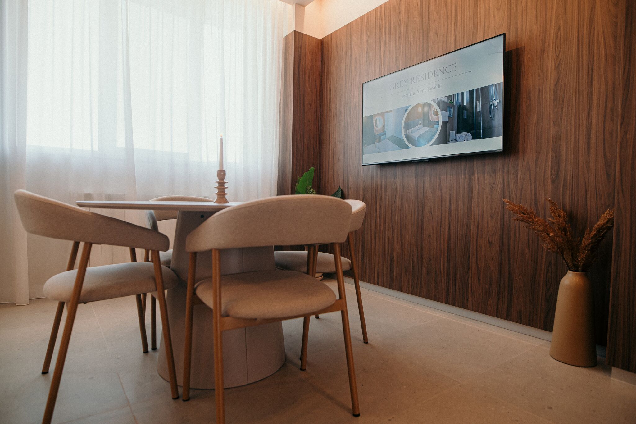 Masa rotunda cu scaune de lemn sub fotografii inramate — Grey Residence, Drobeta-Turnu Severin