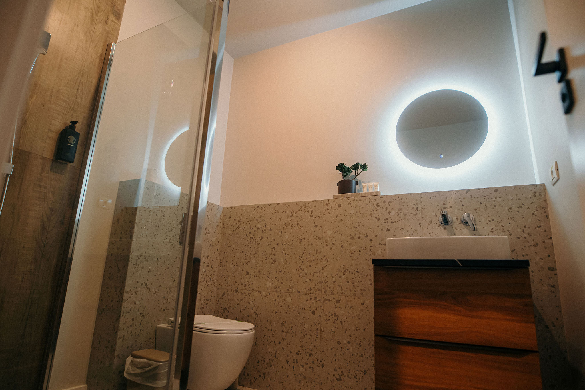 Baie modernă cu duș walk-in, oglindă iluminată și mobilier din lemn